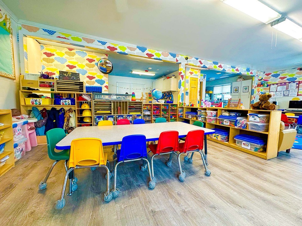 A bright Pine Tree classroom with a group table, colorful chairs, and shelves of learning materials