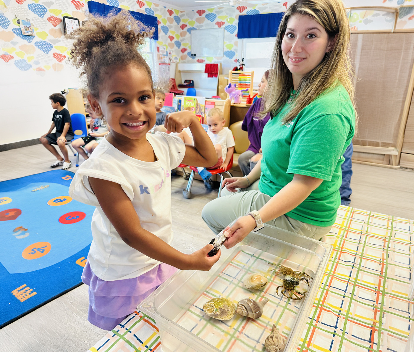 A teacher and a smiling child exploring a sea life sensory bin together