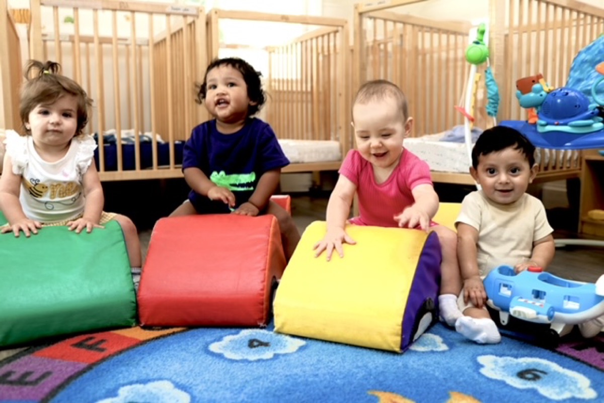 Four babies playing together on soft foam climbing blocks