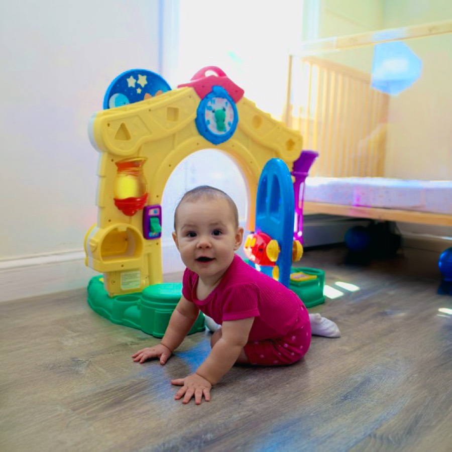A baby crawling toward an activity playhouse in the infant room