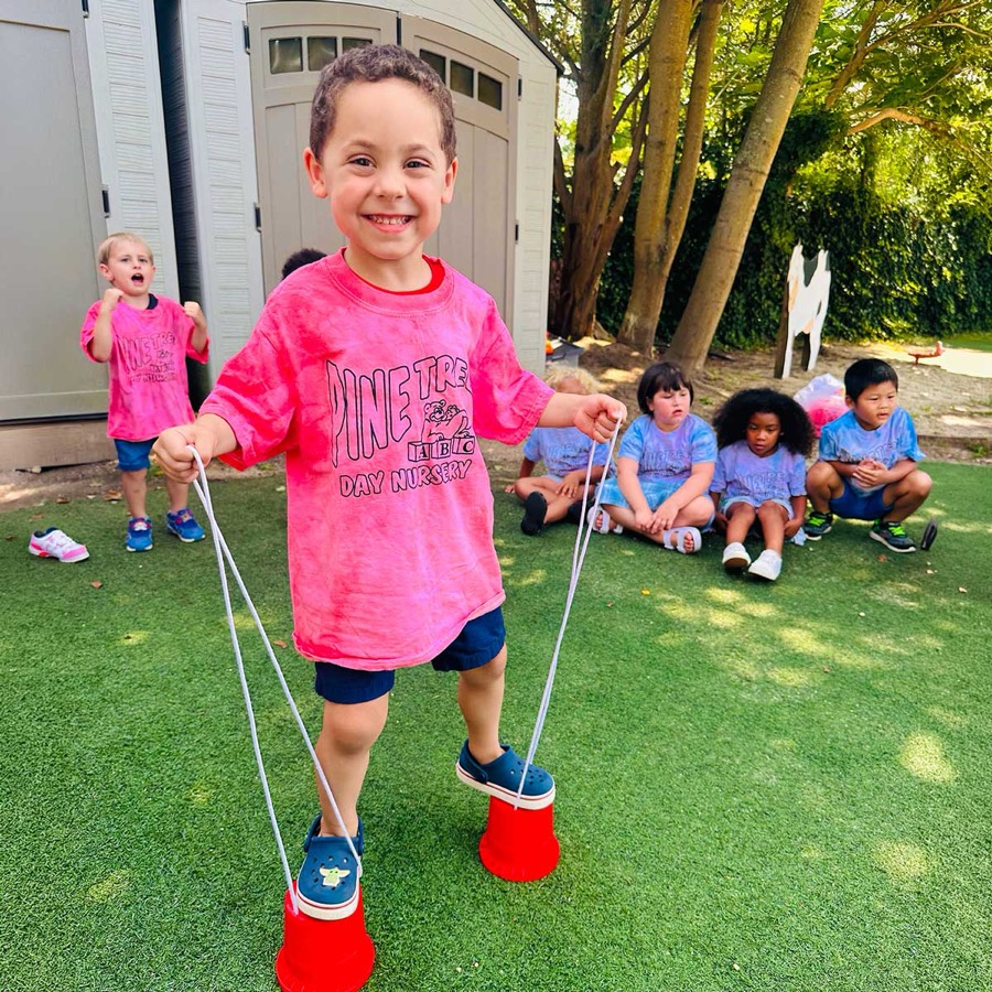 A Pre-K child balancing on stilts on the playground