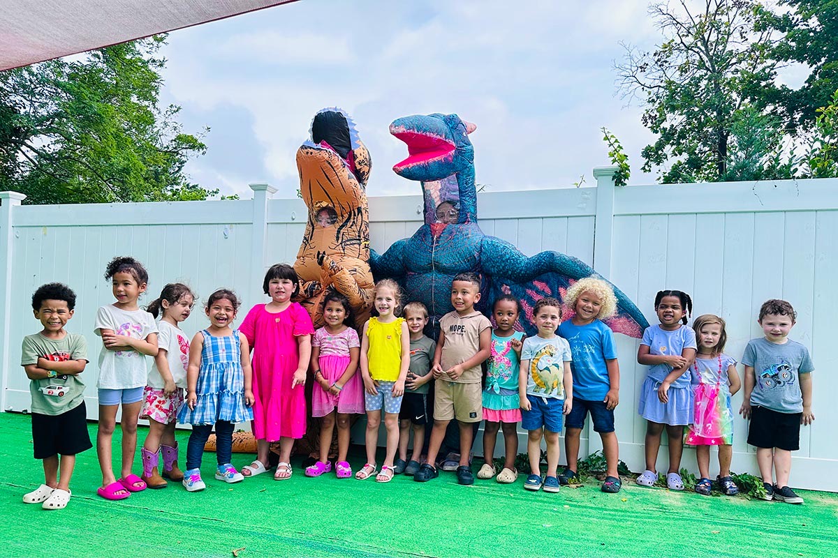 Pre-K children lined up outside with costumed dinosaur visitors