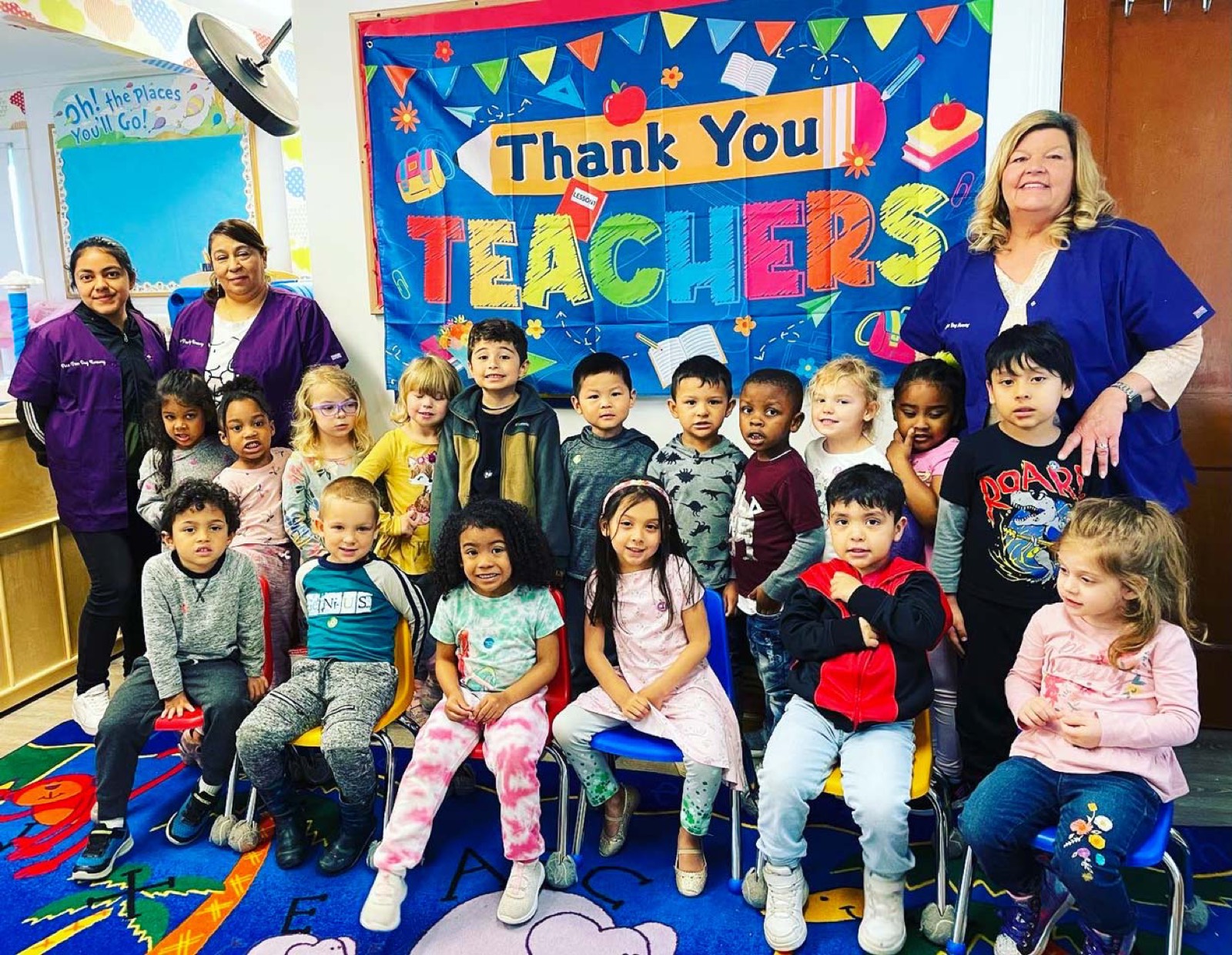 A Pre-K class with their teachers in front of a Thank You Teachers display