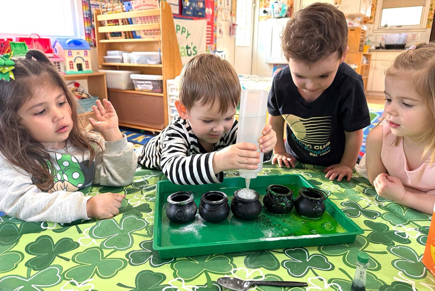 Preschoolers watching a St Patrick's Day science experiment with pots of gold