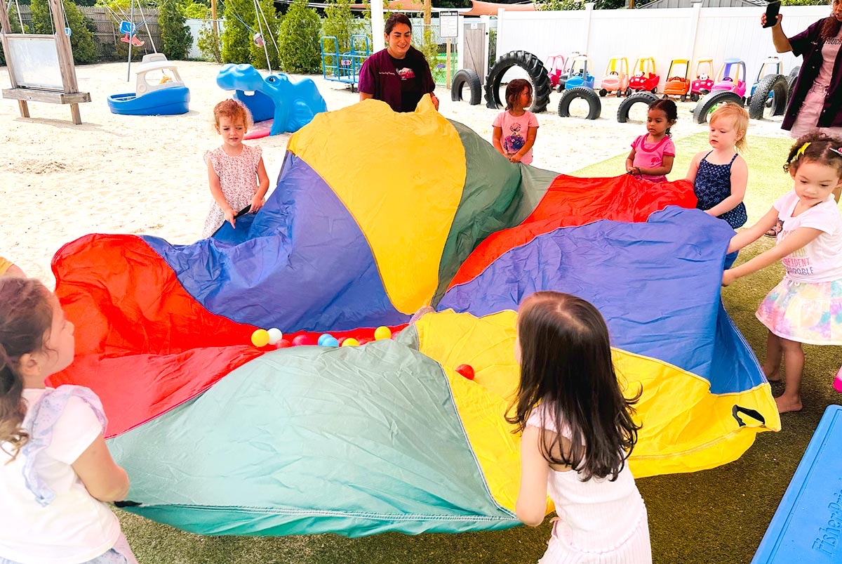 Preschoolers playing a parachute game together on the playground