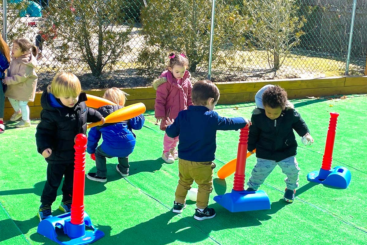Toddlers playing together with t-ball sets on the playground