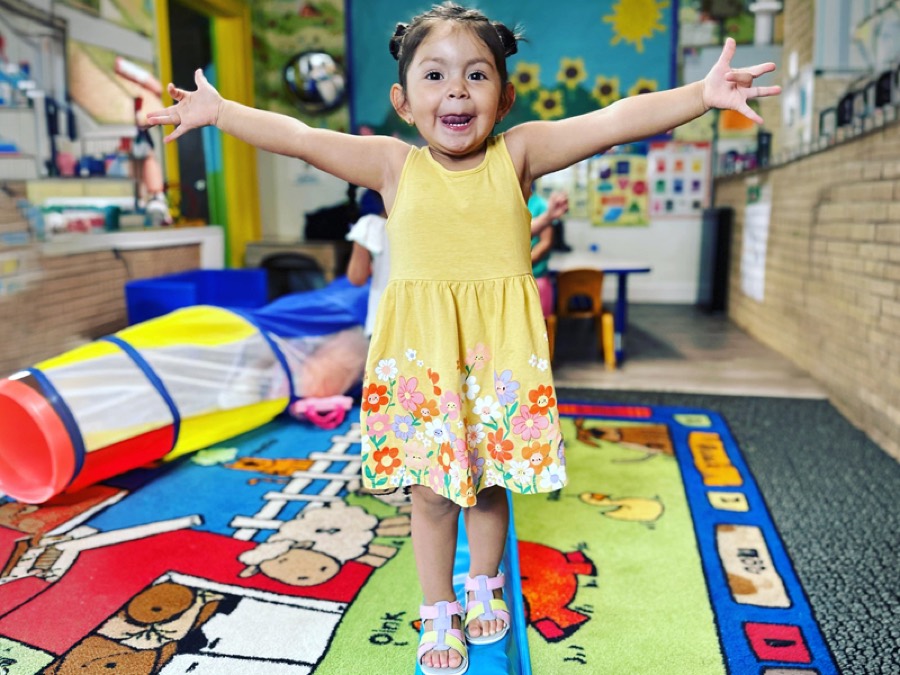 A toddler balancing happily on a play beam